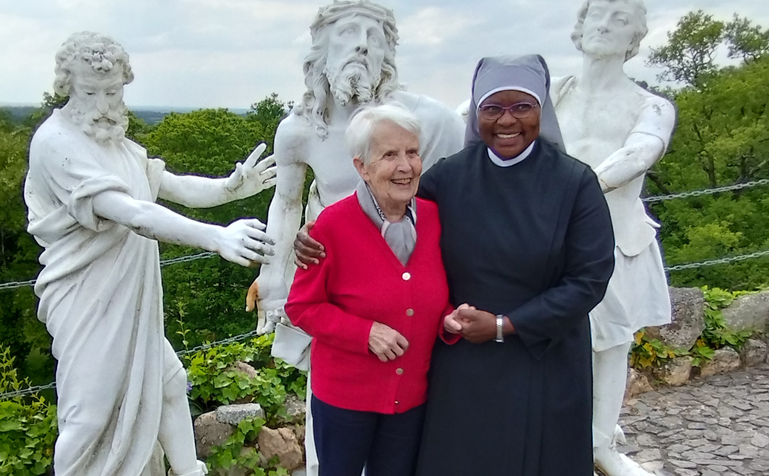 Personne âgée et petite soeur devant une statue