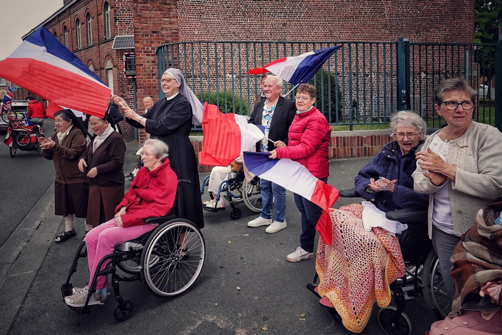 personnes âgées et petites sœurs des pauvres qui tiennent des drapeaux français