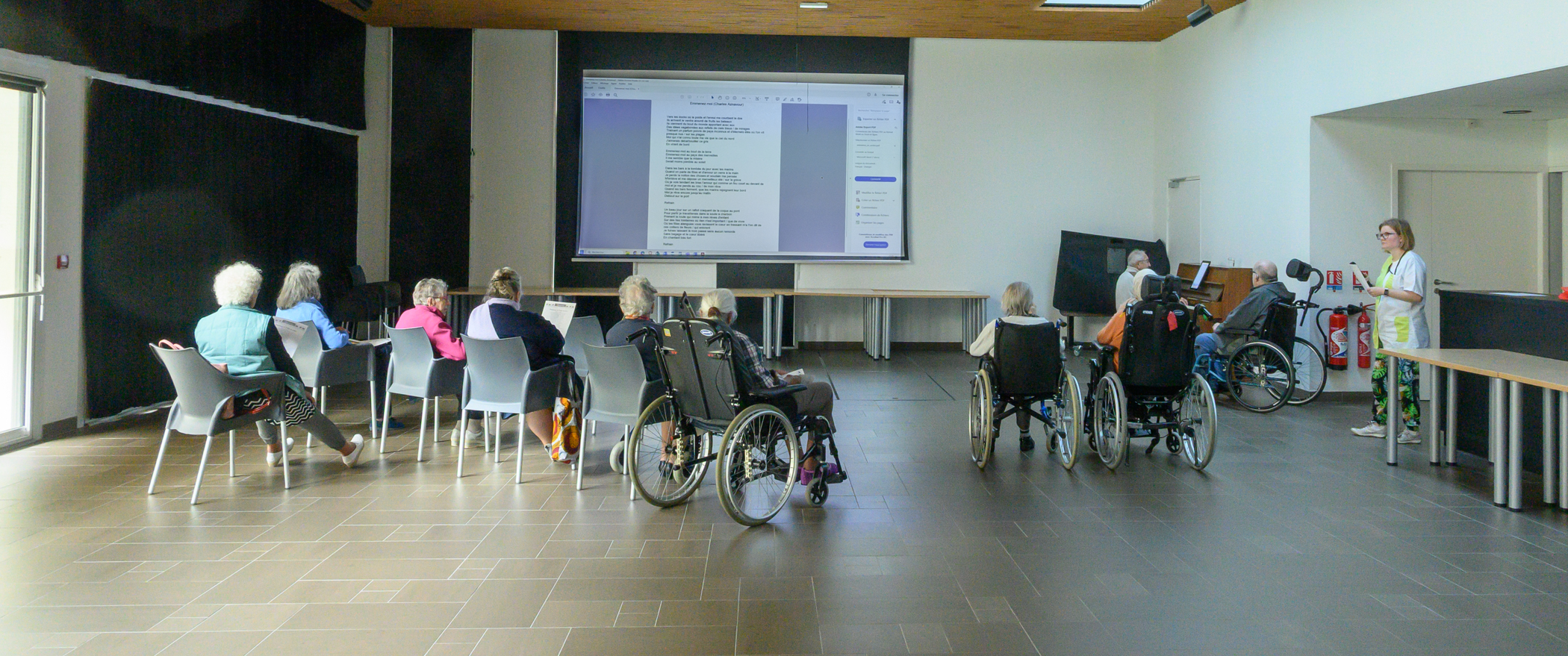 Personnes âgées dans une grande salle qui écoutent du piano