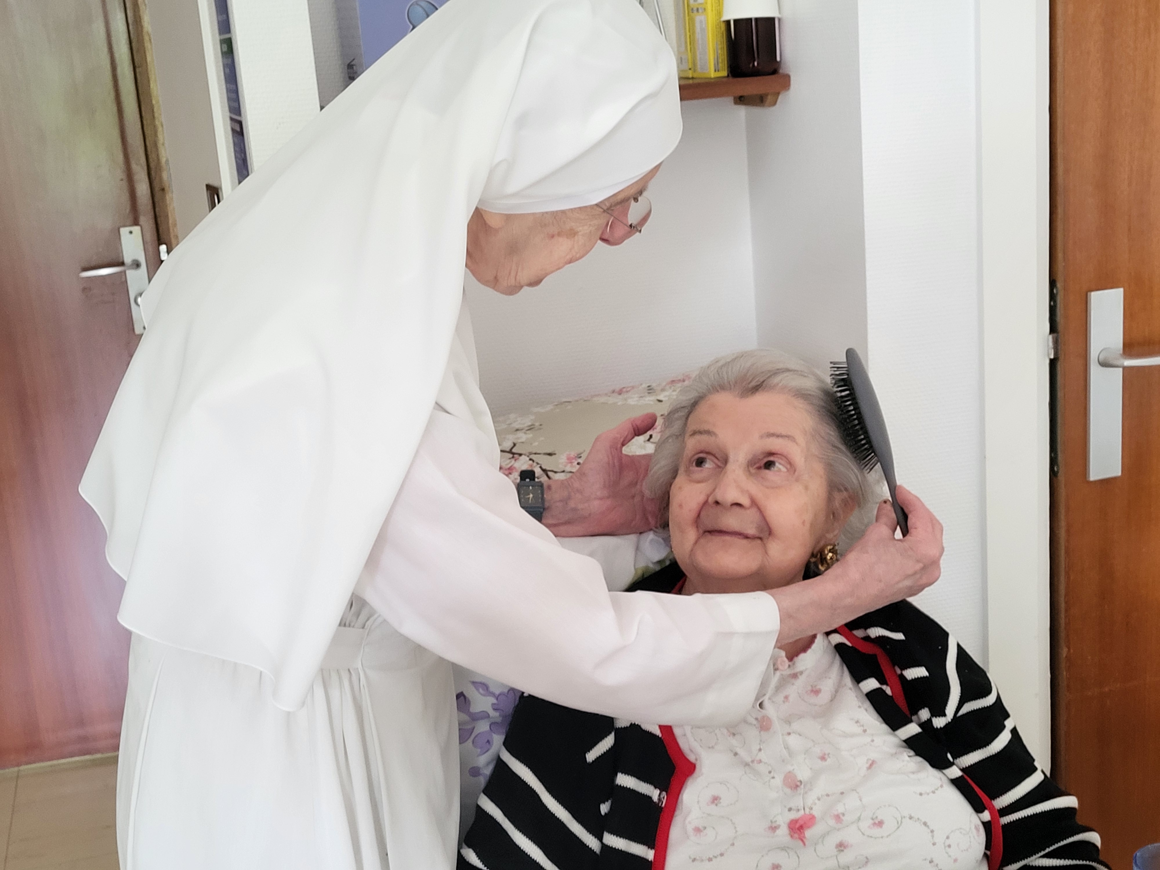 Petite soeur qui coiffe une personne âgée