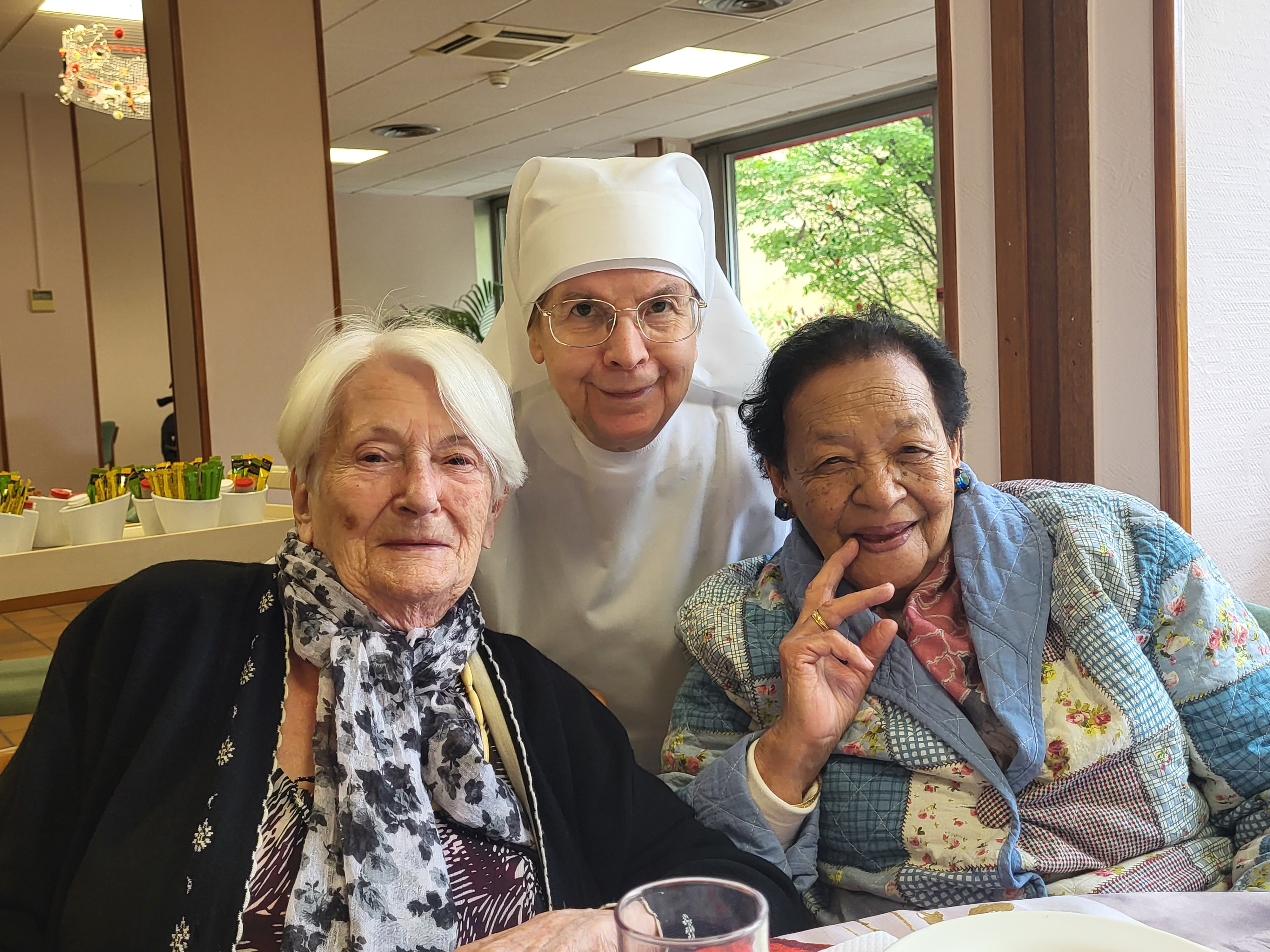 Petite soeur et deux personnes âgées qui posent dans une salle à manger