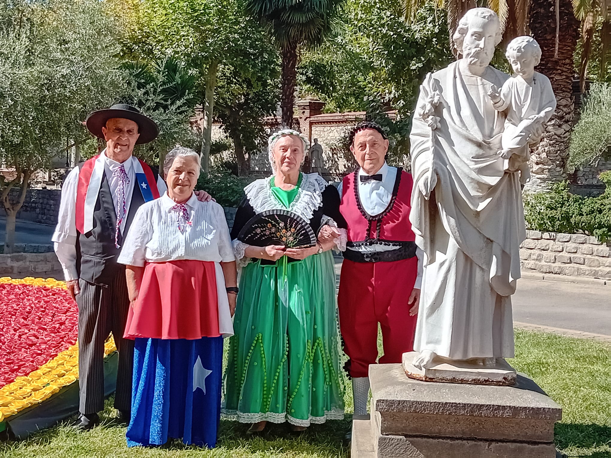 Personnes âgées en costumes traditionnels devant une statue de sainte Jeanne Jugan