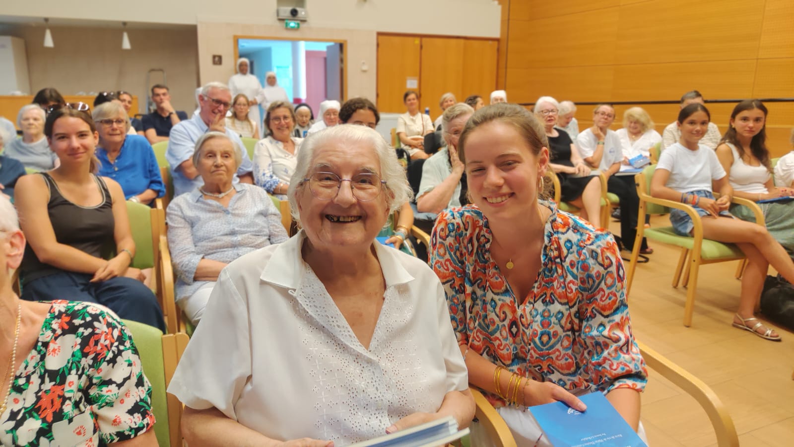 Personne âgée et jeunes assises dans une salle