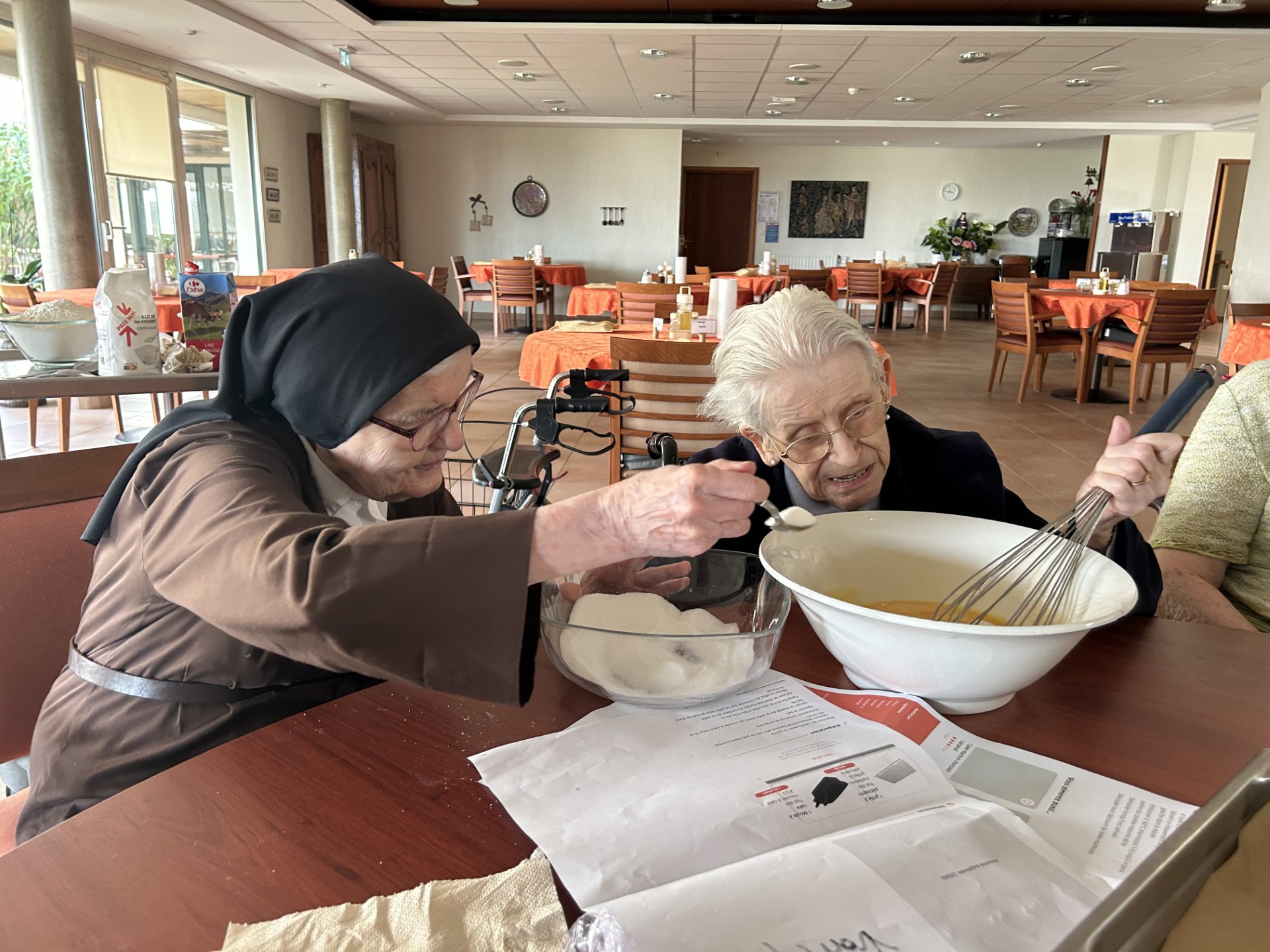 Soeur et personne âgée qui font un atelier patisserie