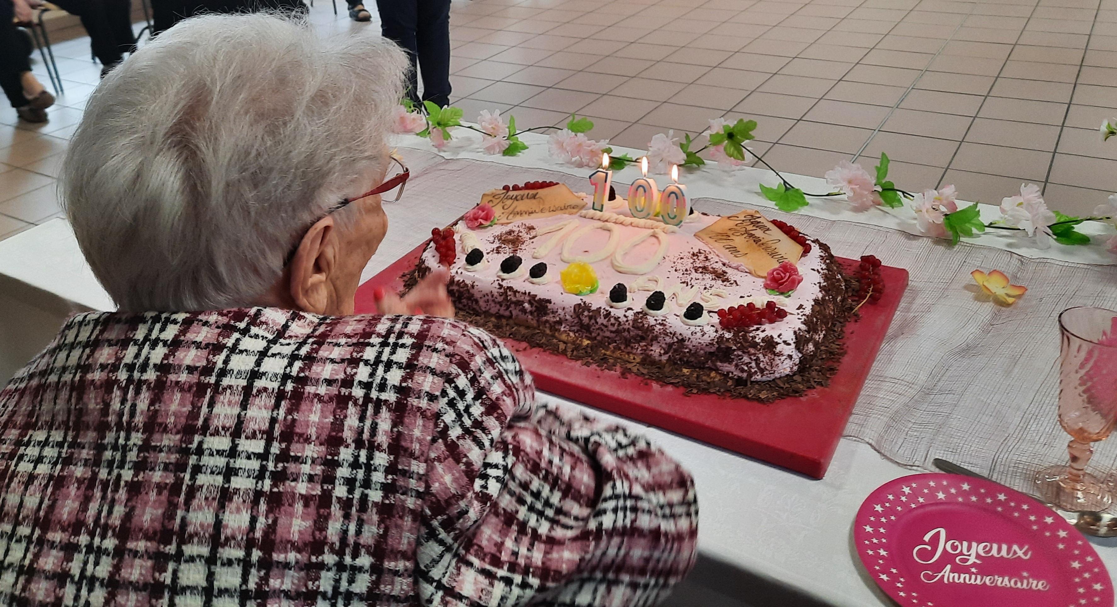 Personne âgée qui souffle un gâteau d'anniversaire pour ses 100 ans