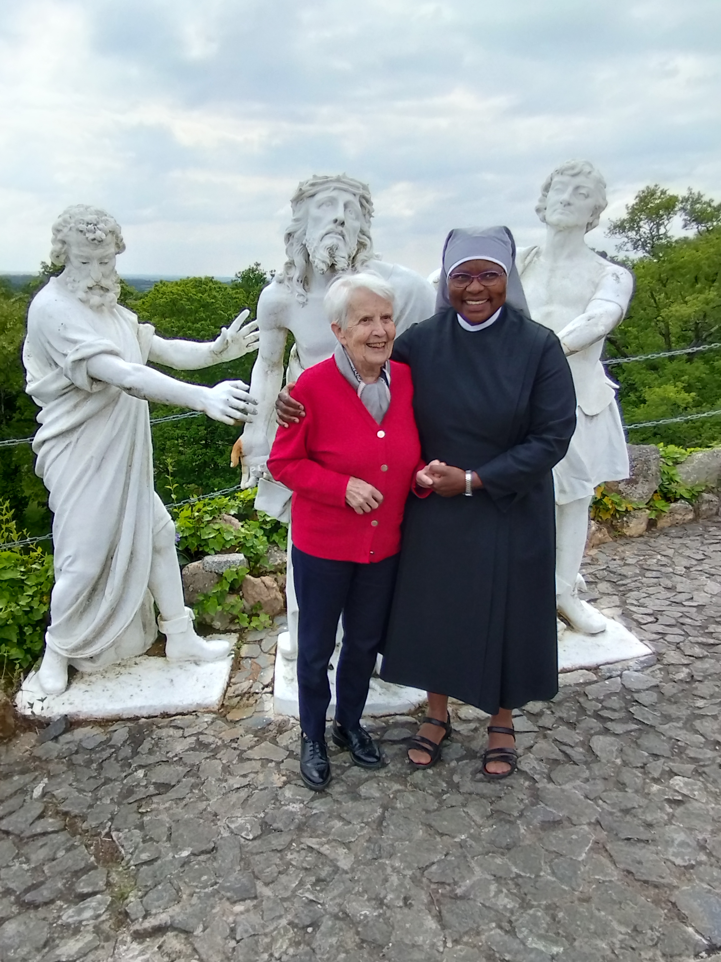 1 personne âgée et une petite sœurs devant des statues