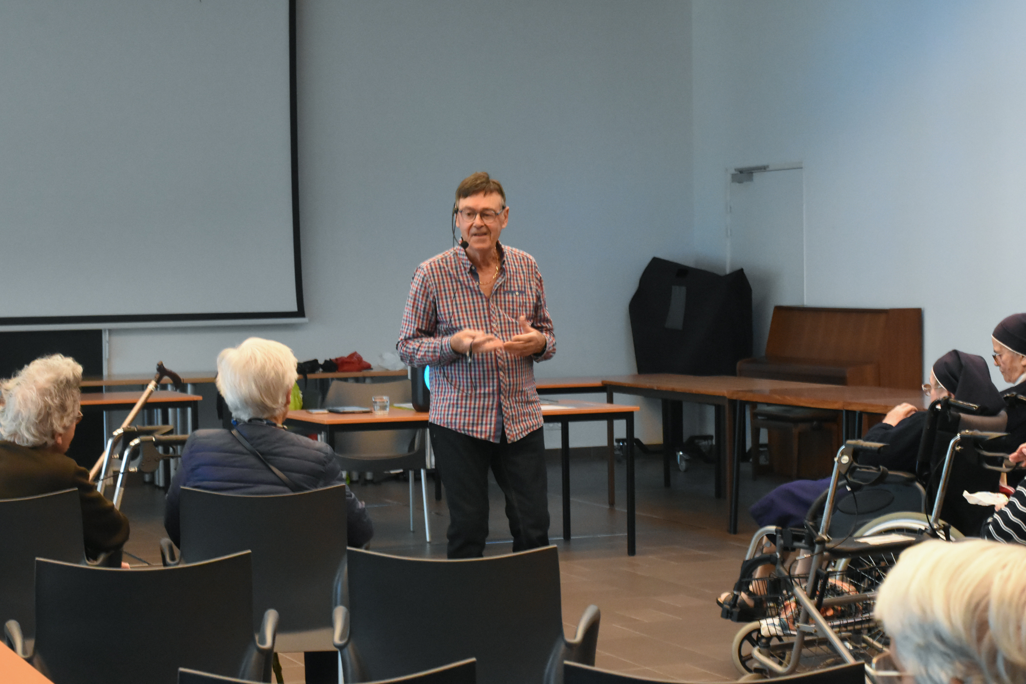 Personne qui déclame un poème dans une salle devant des personnes âgées